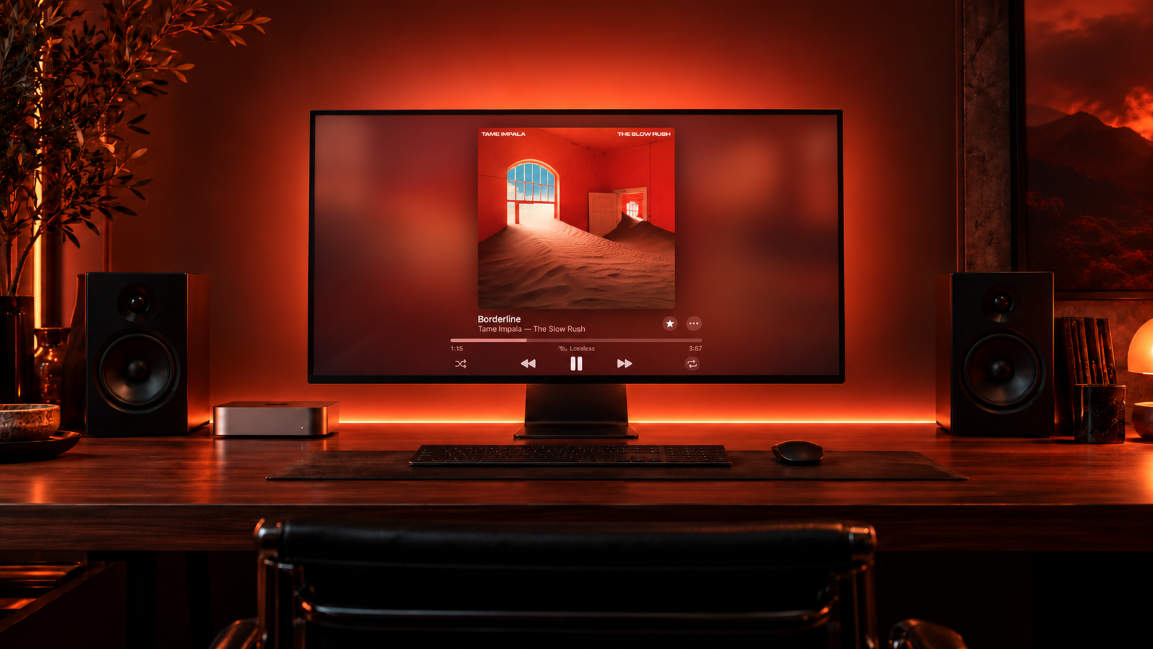 A Mac listening setup with red-orange lighting behind the display and desk