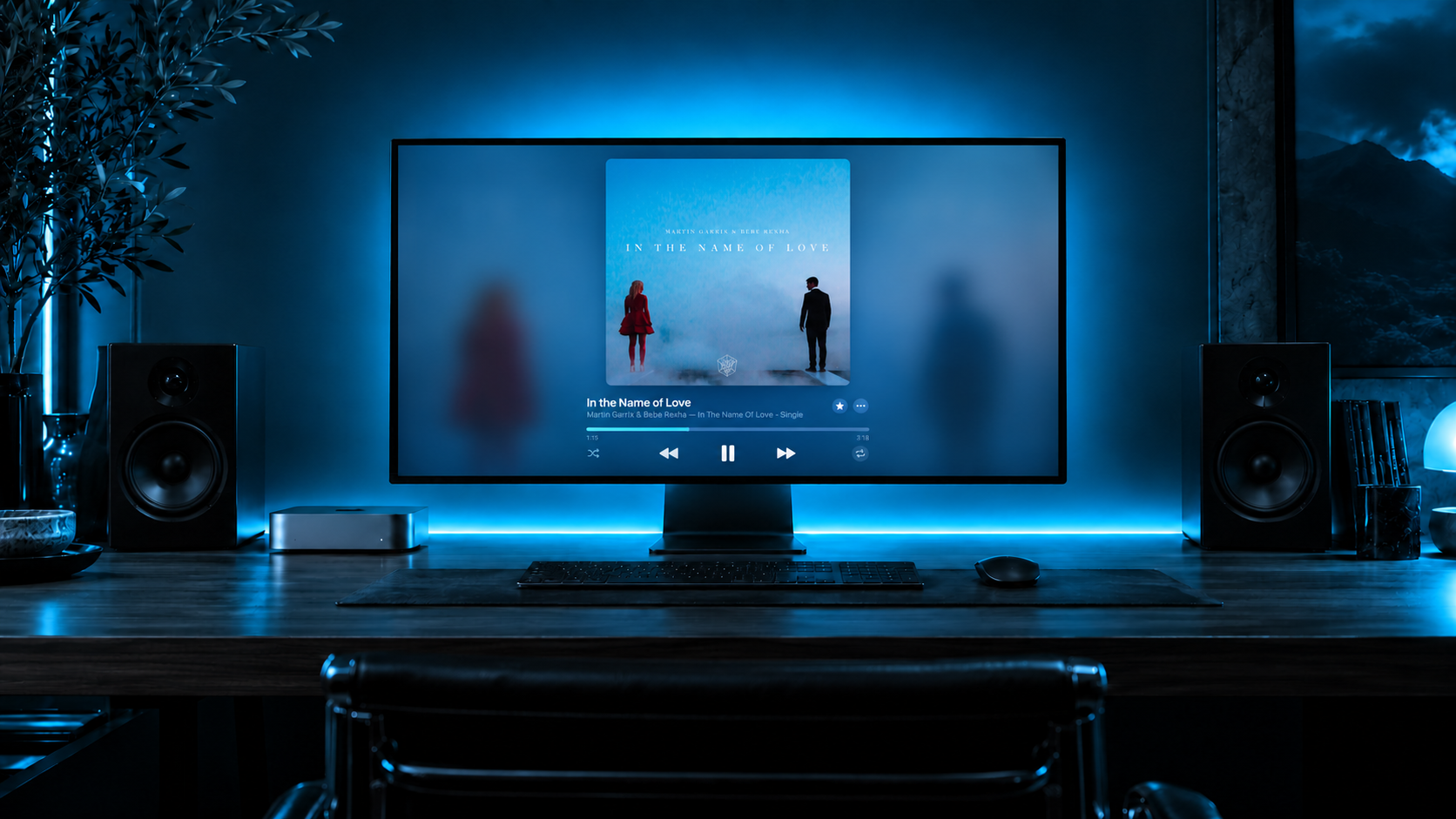 A Mac listening setup with blue lighting behind the display and desk