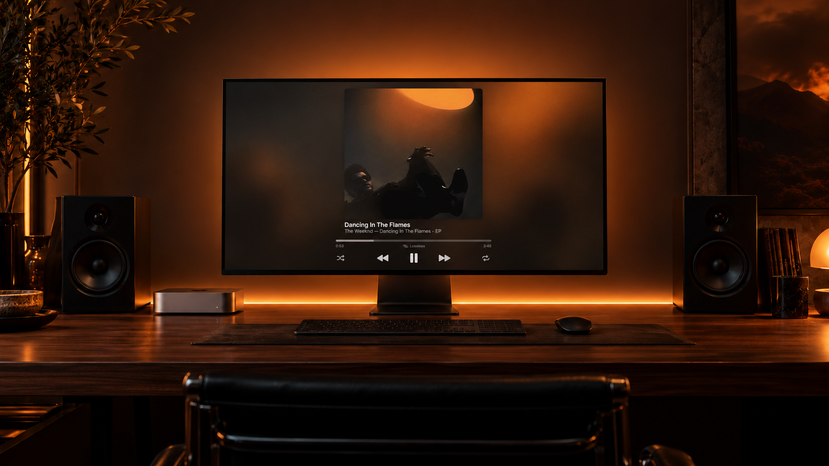 A Mac listening setup with amber lighting behind the display and desk